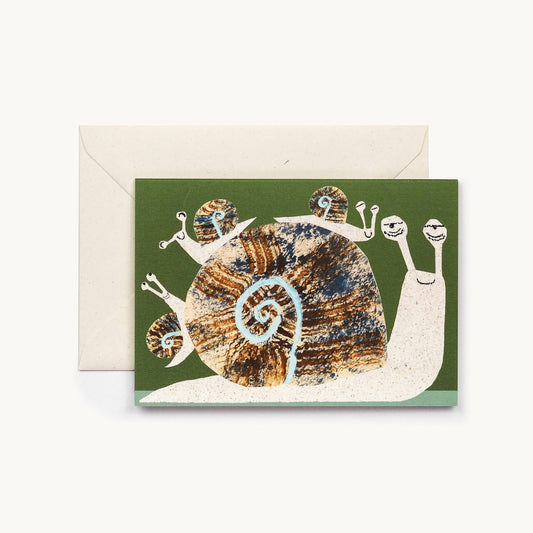 Olive green greeting card with an illustrated giant snail carrying four smaller baby snails on its shell, cream envelope behind