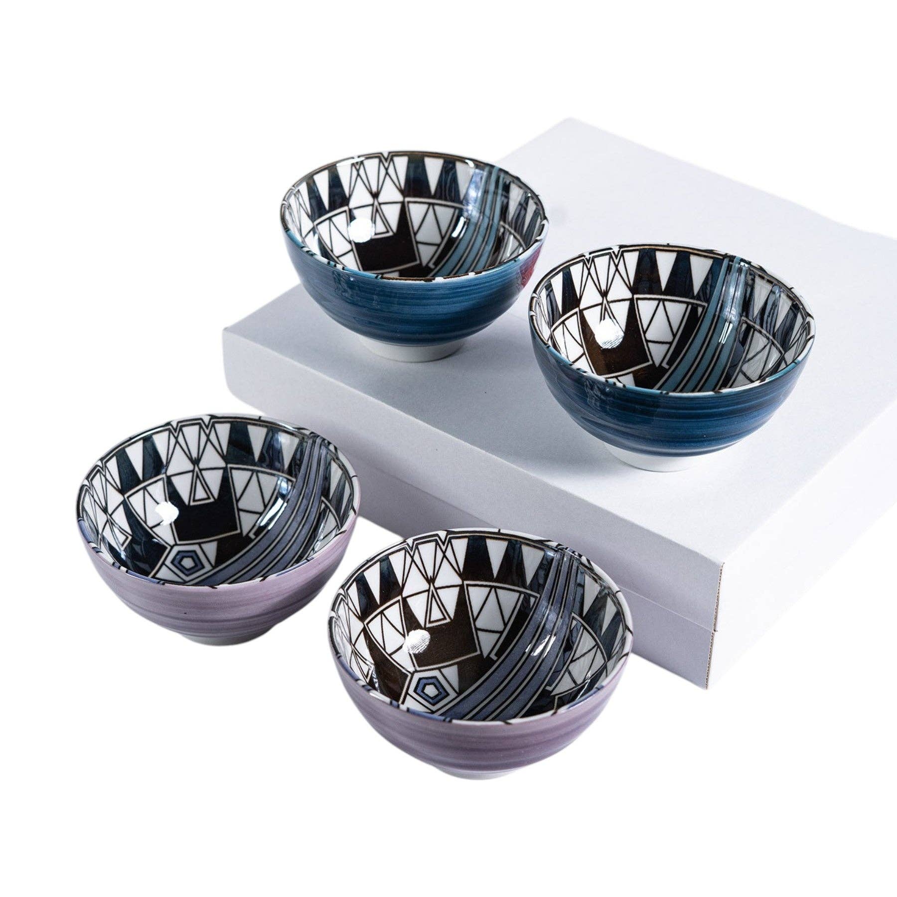 Four Frank Lloyd Wright Peacock-pattern porcelain bowls in blue-black and plum-black Art Deco geometric designs, two raised on a white pedestal box