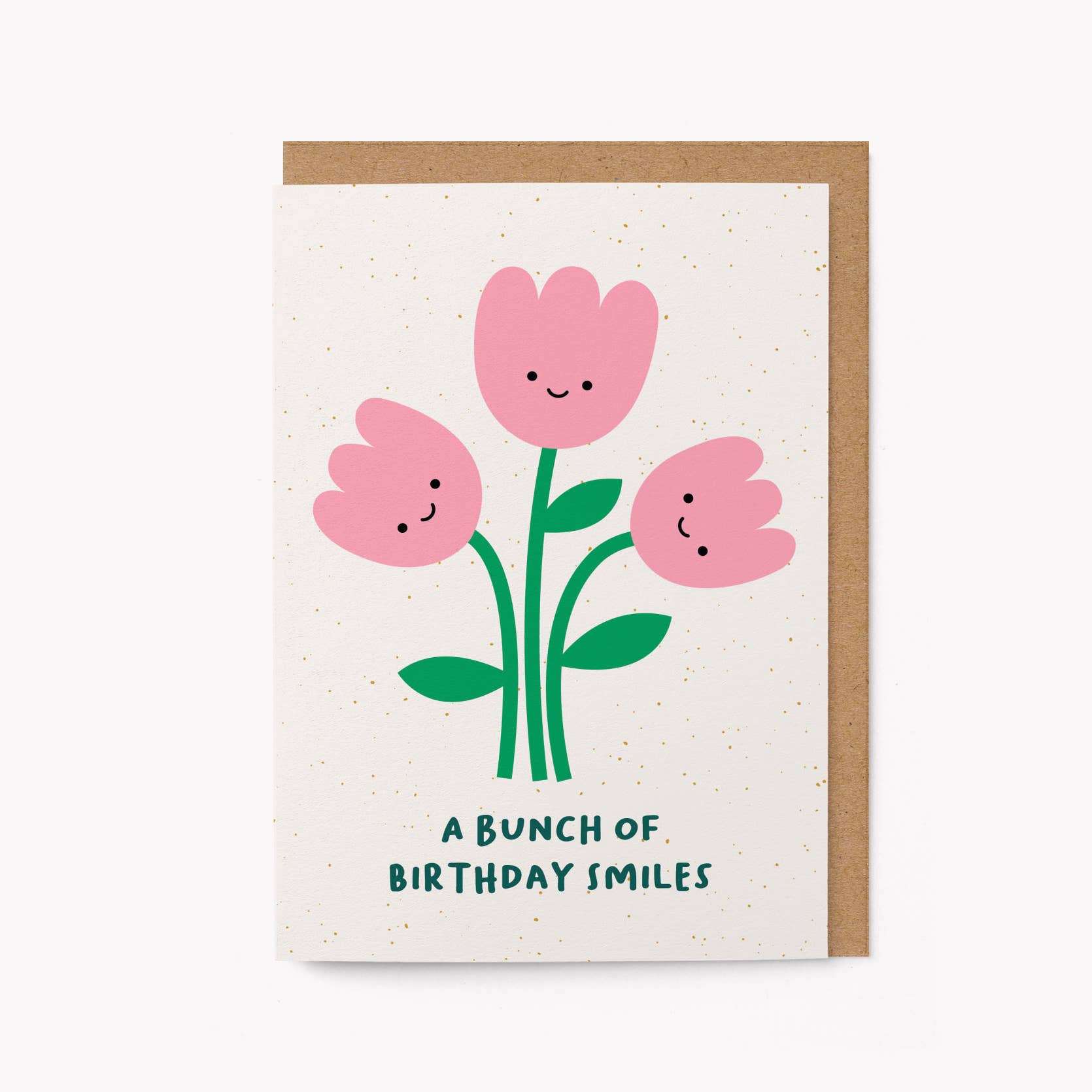 Cream greeting card with three illustrated smiling pink tulips and the text 'A Bunch of Birthday Smiles,' kraft envelope alongside