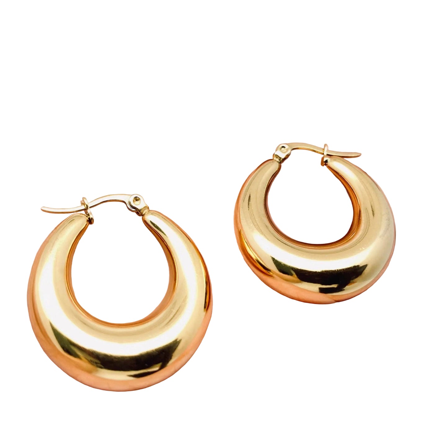 Gold hoop earrings held in a hand against a white background