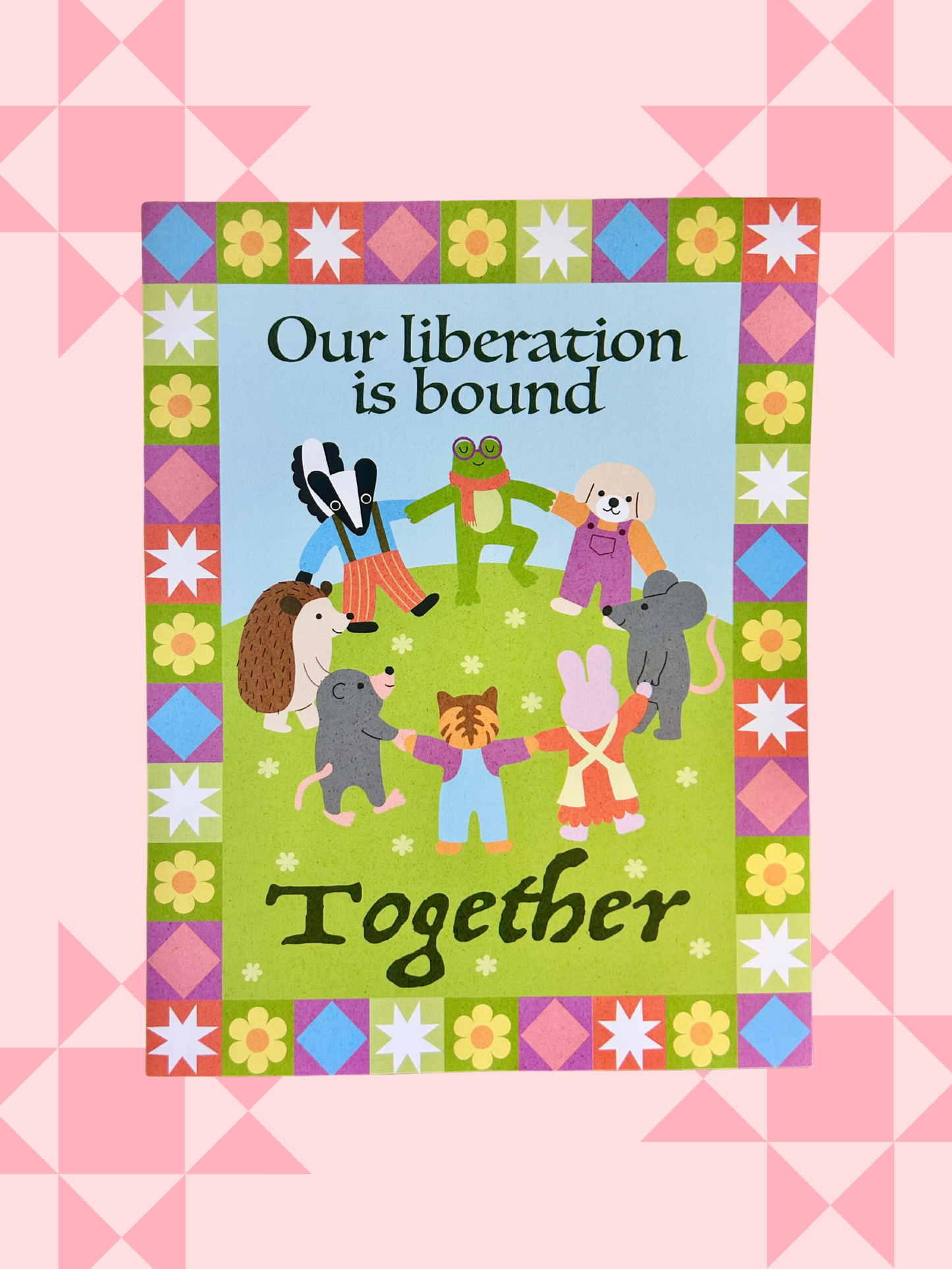 Illustrated print of animal characters holding hands in a circle on a quilt-patterned border, reading Our liberation is bound together