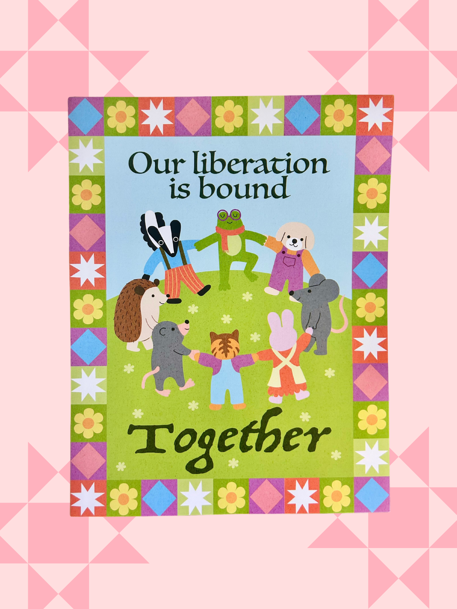 Illustrated print of animal characters holding hands in a circle on a quilt-patterned border, reading Our liberation is bound together