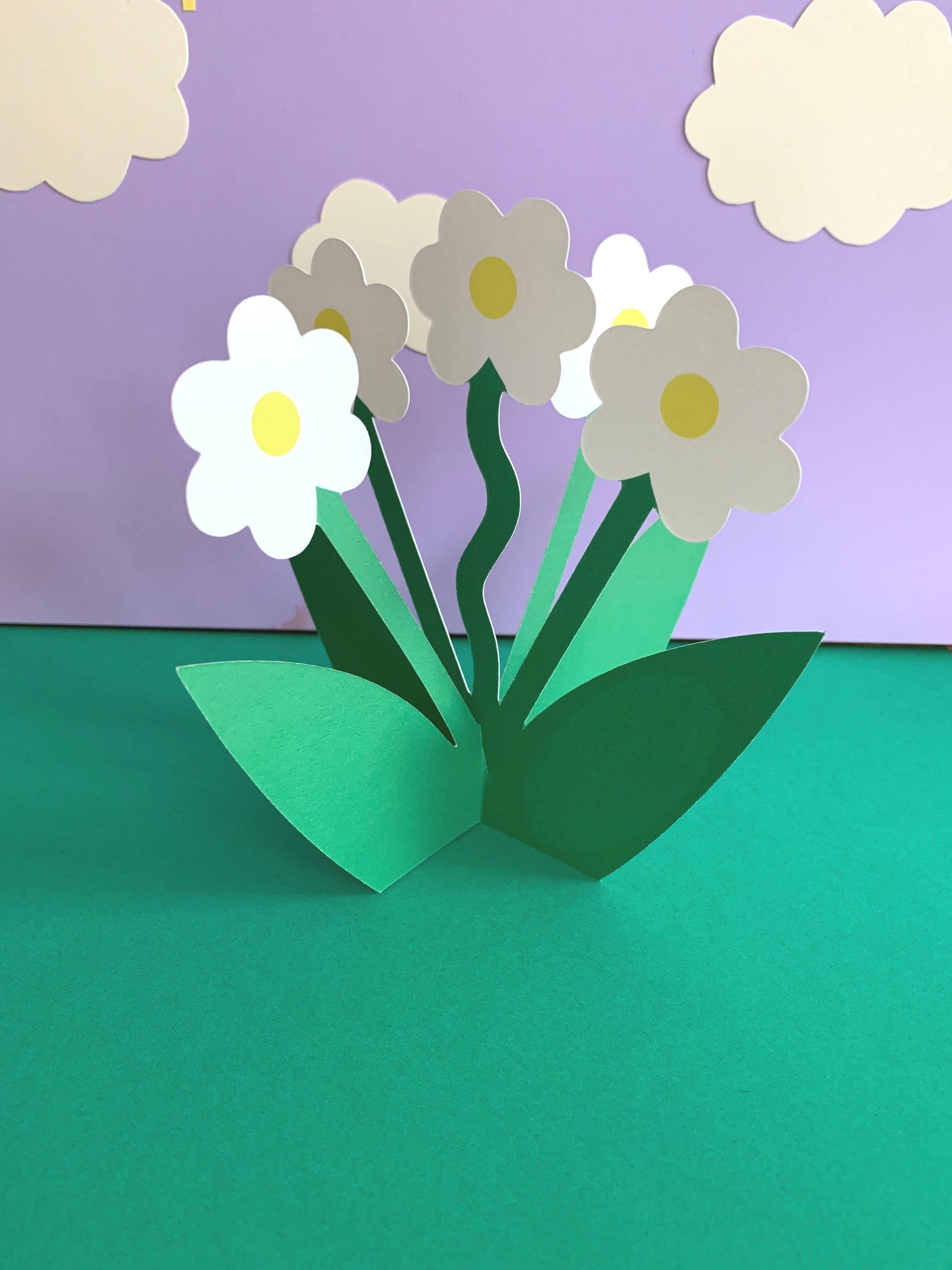 Kitty Kenda die-cut standing daisy bouquet greeting card with white flowers and green stems, shown standing upright