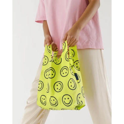 Baby Baggu with a smiley face pattern being held in the hand - PABOOM