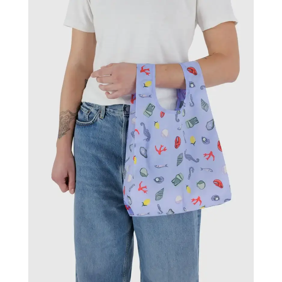 Baby Baggu bag featuring a pattern of seaside trinkets being held in the arm