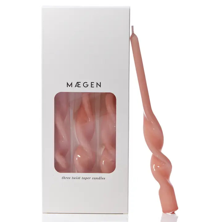 MÆGEN twist taper candle in glossy plaster pink leaning against its white branded box printed "three twist taper candles"
