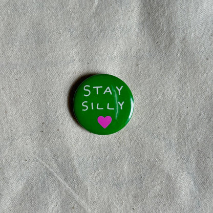 Green pinback badge reading Stay Silly with a pink heart, on linen fabric - PABOOM