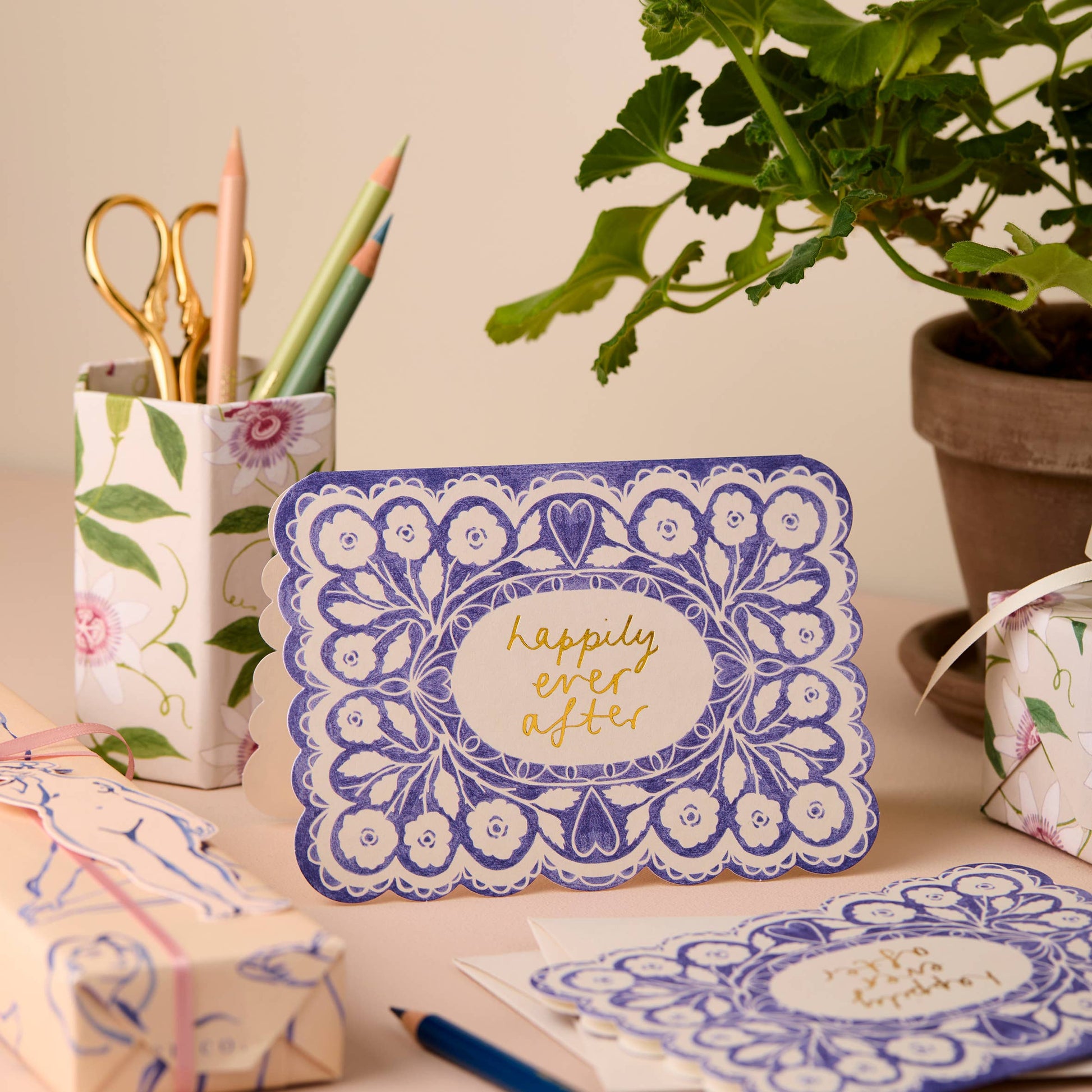 Cornflower blue lace-pattern card with a gold script center reading Happily Ever After