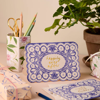 Cornflower blue lace-pattern card with a gold script center reading Happily Ever After