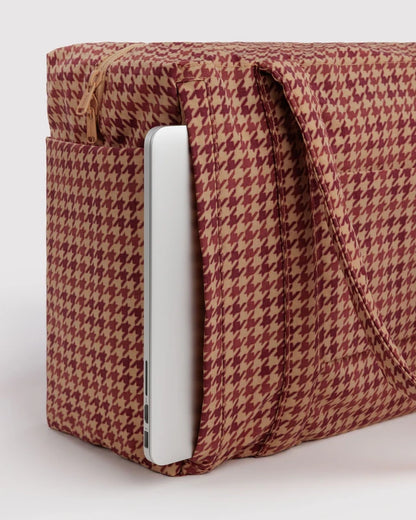 Model carrying the BAGGU Small Cloud Carry-On in tan houndstooth over one shoulder