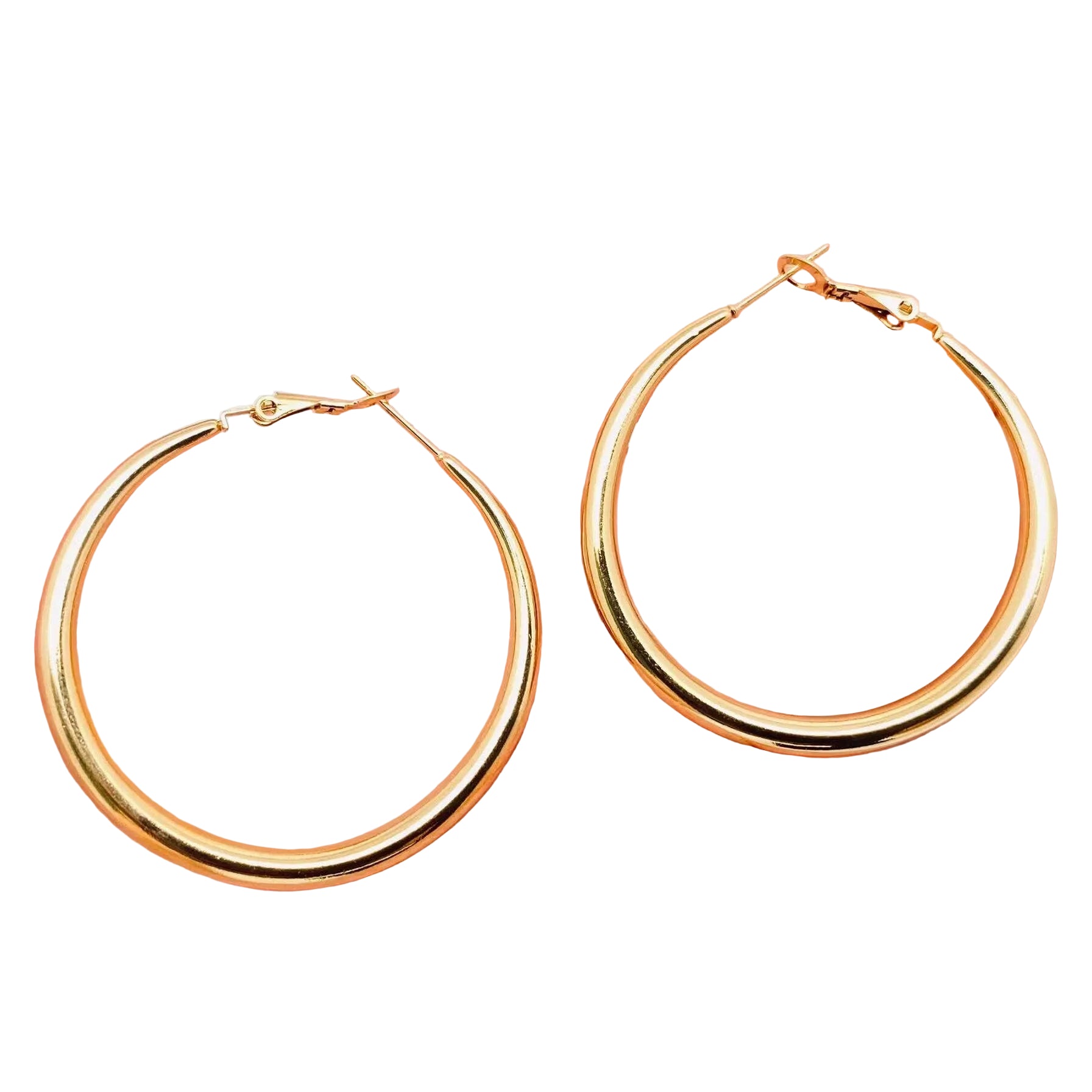 Gold hoop earrings held in a hand against a light background