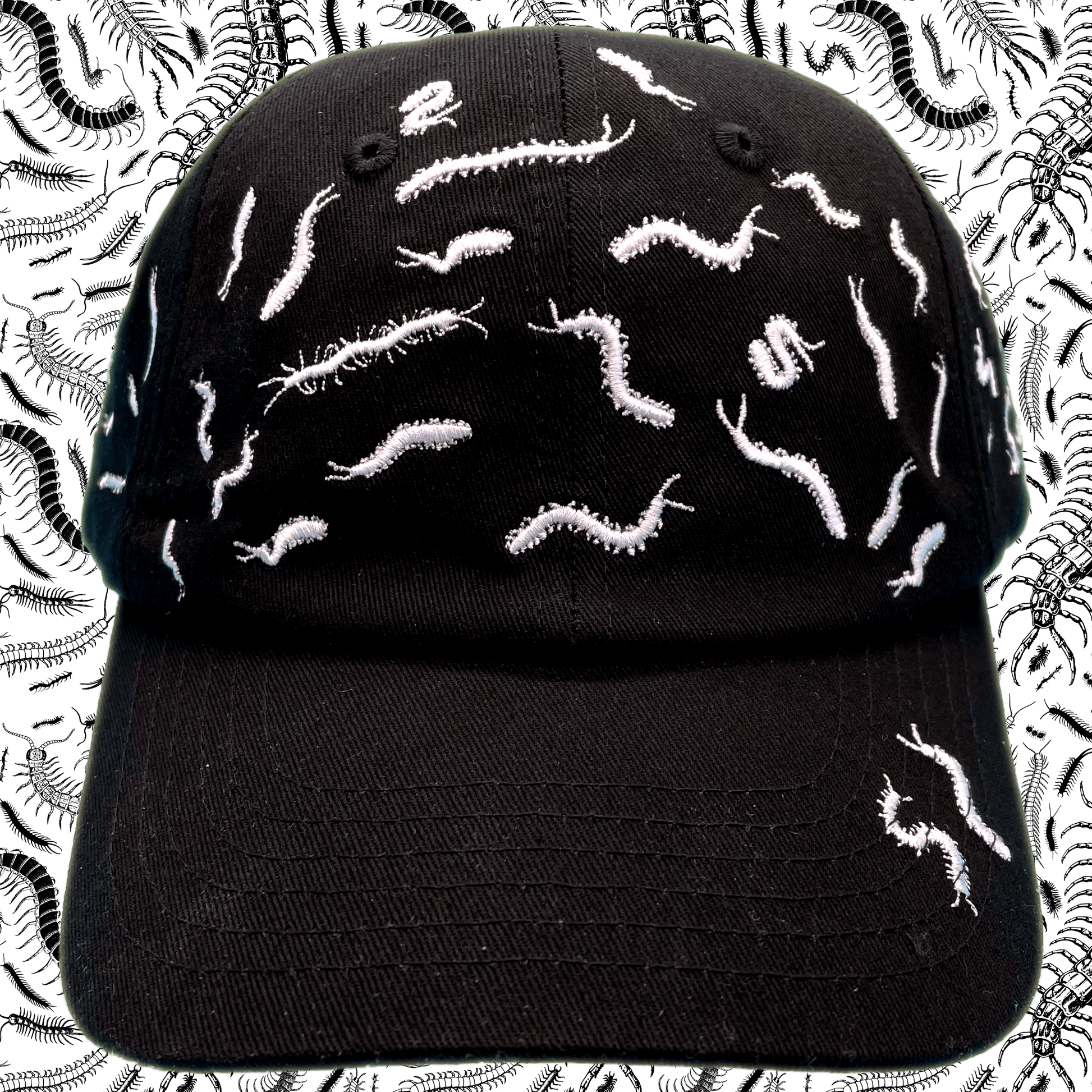 Black dad hat covered in white embroidered centipede designs scattered across the crown and brim, front view, with a centipede-print background.