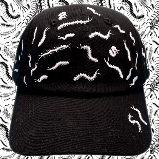 Black dad hat covered in white embroidered centipede designs scattered across the crown and brim, front view, with a centipede-print background.