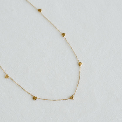 Golden Heartline necklace with small heart charms spaced along a fine gold chain - PABOOM