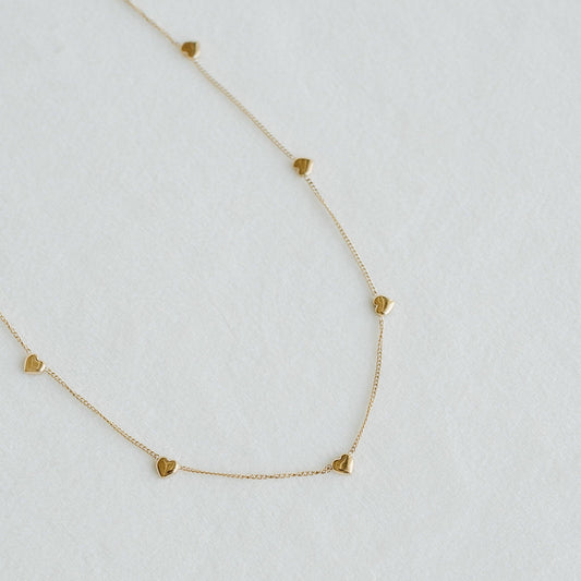 Golden Heartline necklace with small heart charms spaced along a fine gold chain - PABOOM
