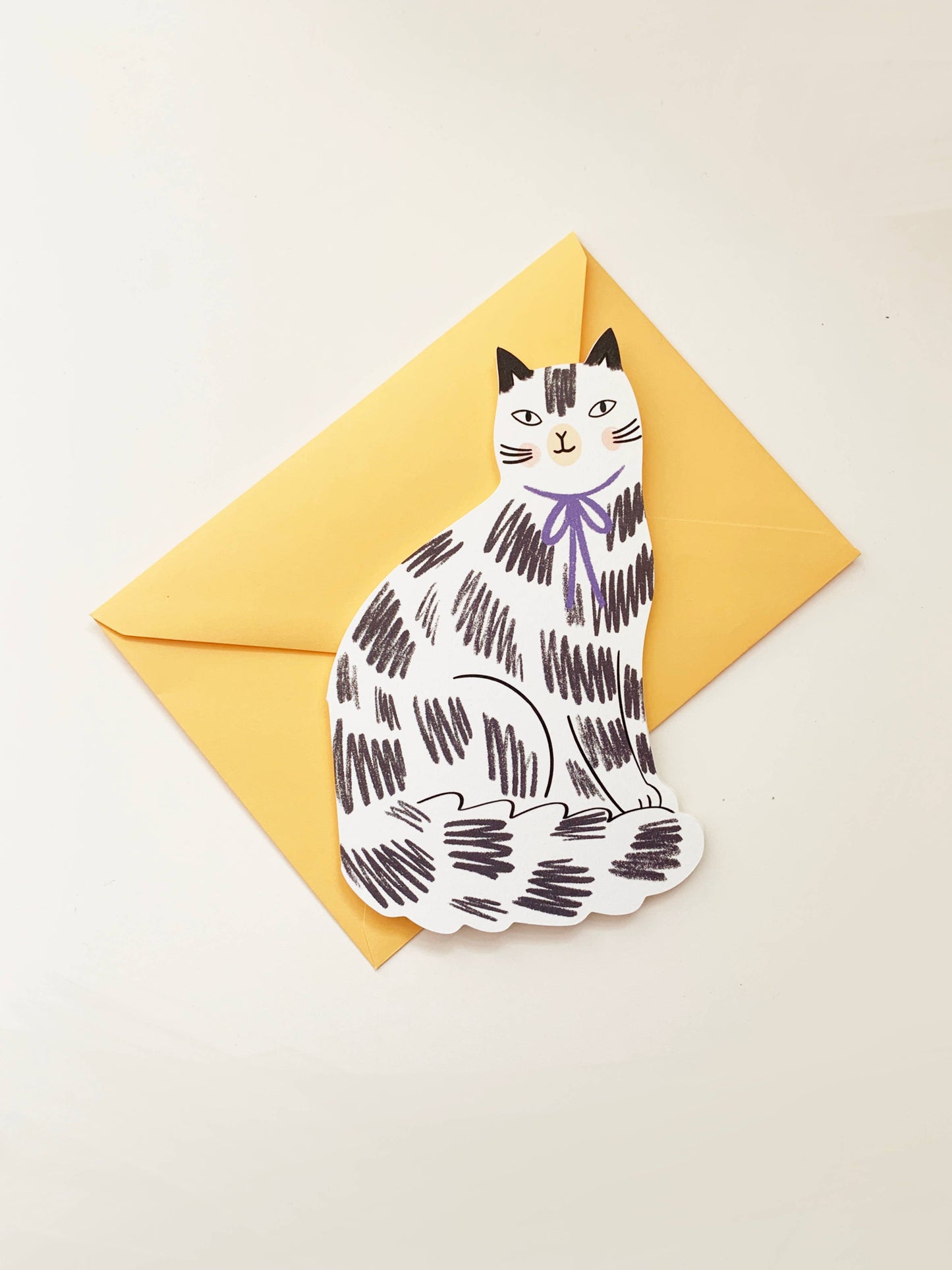 Kitty Kenda shaped sitting cat greeting card with a black and white scribbled tabby pattern and purple bow