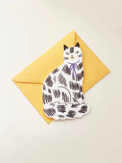 Kitty Kenda shaped sitting cat greeting card with a black and white scribbled tabby pattern and purple bow