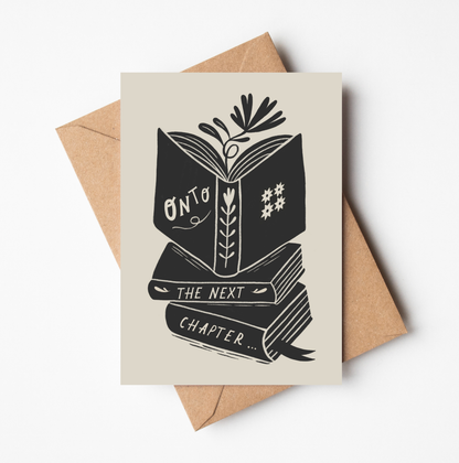 'Onto The Next Chapter...' card featuring a bold black illustration of an open book atop a stack of books, with botanical details, on a cream background