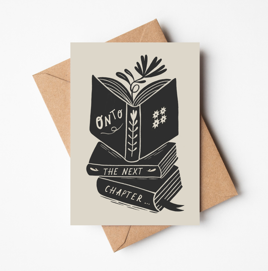 'Onto The Next Chapter...' card featuring a bold black illustration of an open book atop a stack of books, with botanical details, on a cream background