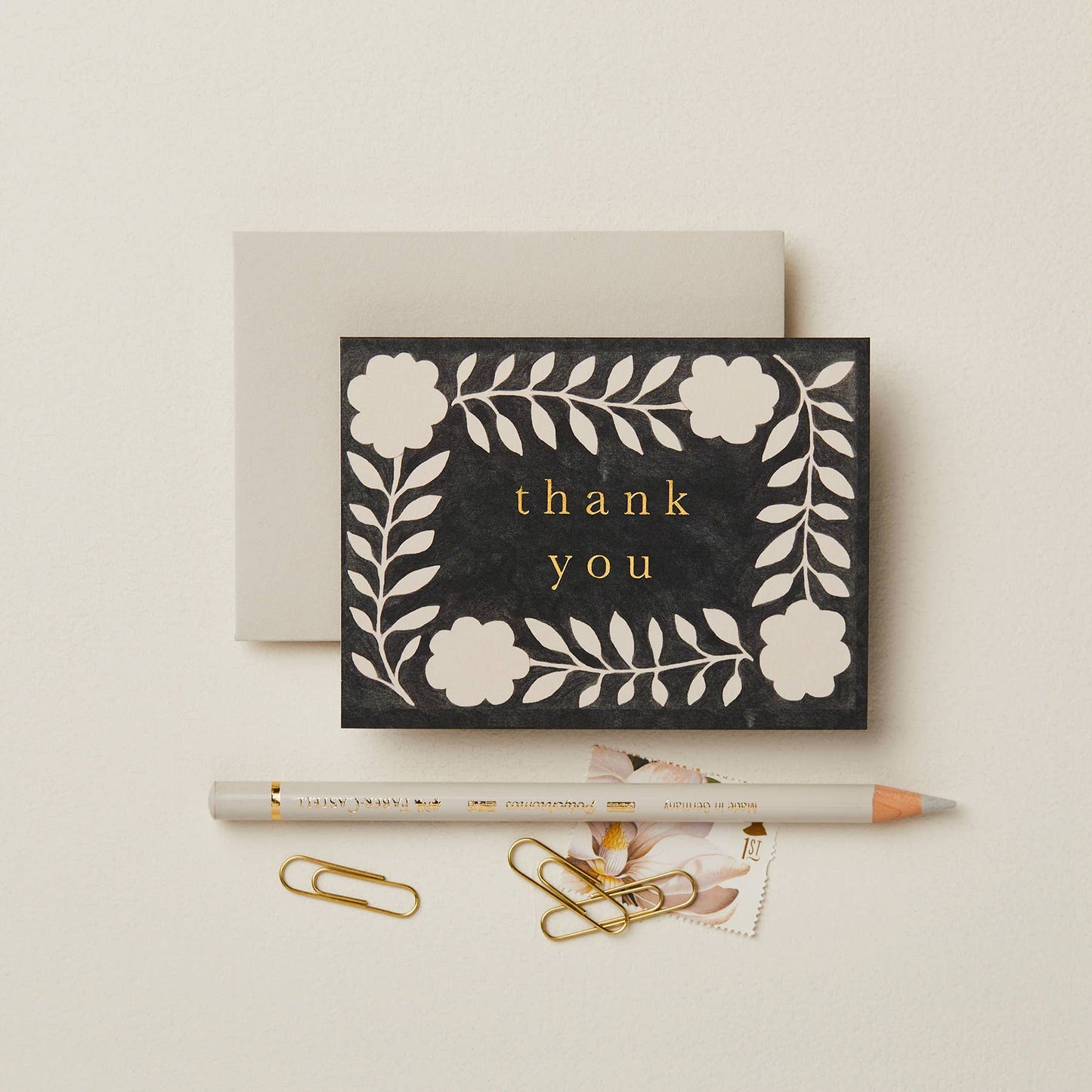 Black textured card with a cream floral wreath pattern, reading Thank You in gold script