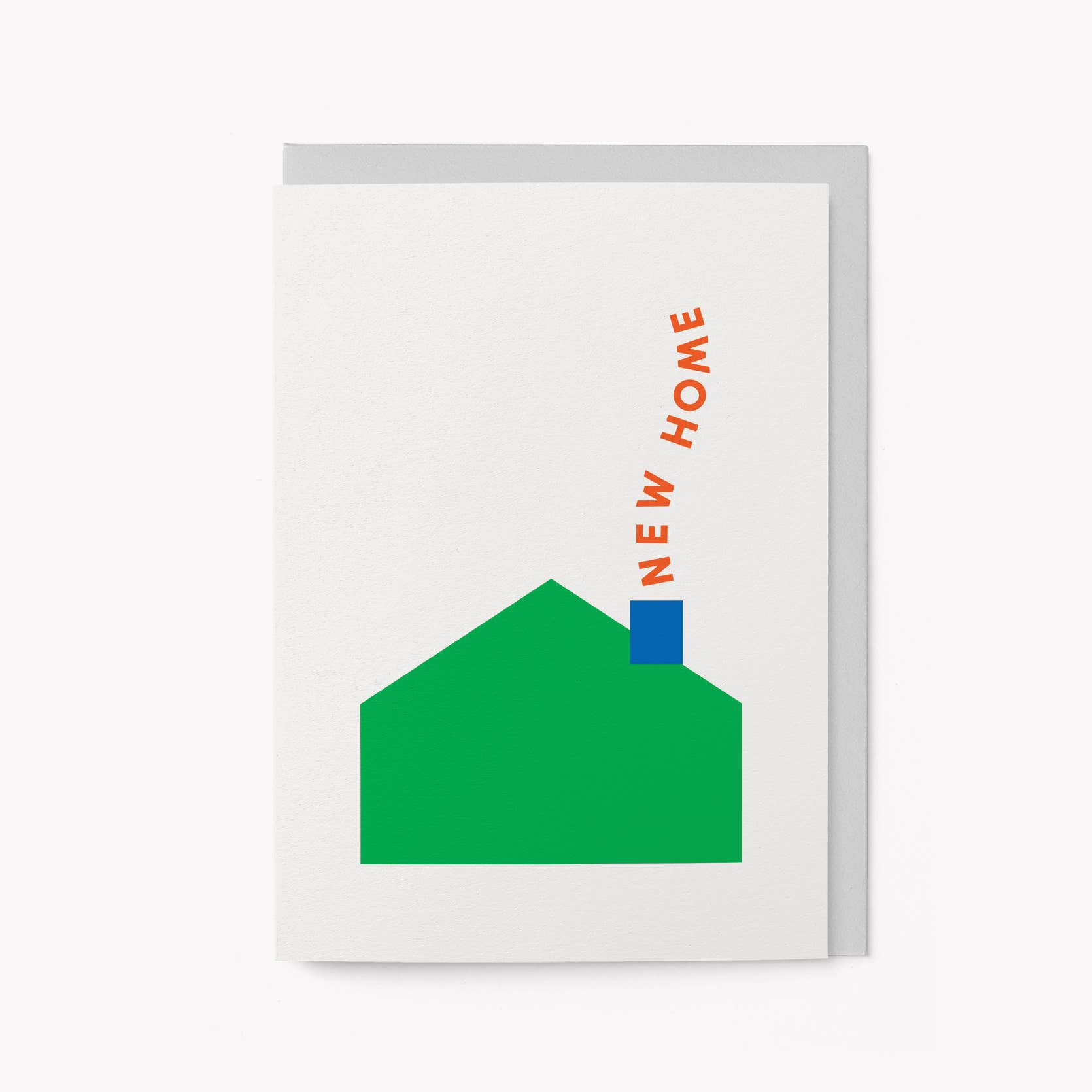 Cream greeting card with a minimalist green house illustration and a blue chimney, with 'NEW HOME' text curving up from the chimney like smoke