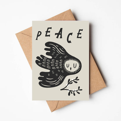 'Peace' Christmas card featuring a black illustrated owl in flight beneath the word 'PEACE', with a small sprig of berries, on a cream background