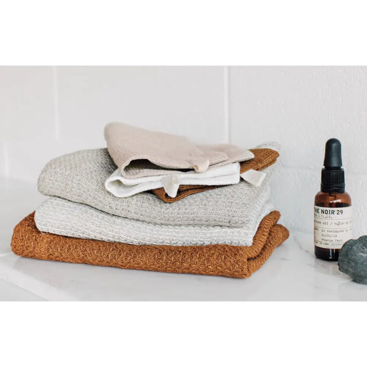 Danica - Amber Linen Hand Towel - stacked folded towels skincare bottle