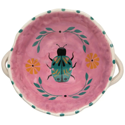 Pink ceramic dish with a beetle design on a white background