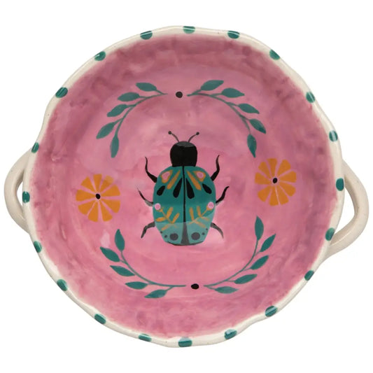 Pink ceramic dish with a beetle design on a white background