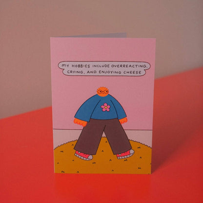 Illustrated greeting card reading 'My hobbies include overreacting, crying, and enjoying cheese' - PABOOM