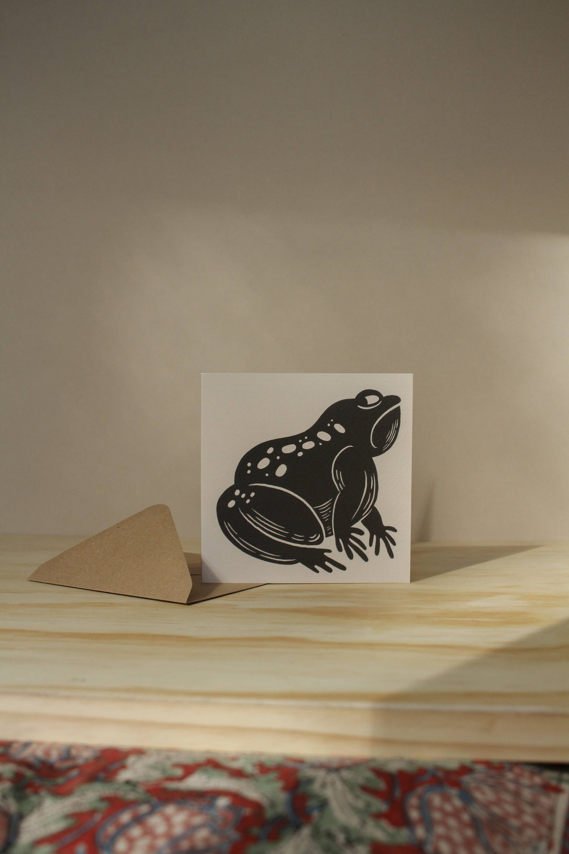 'The Grumpy Frog' card laid flat beside its kraft envelope on a light background
