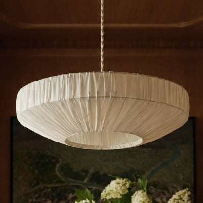 Plissé pleated ivory fabric saucer pendant light hanging from a braided cord in a warm wood-panelled room - PABOOM