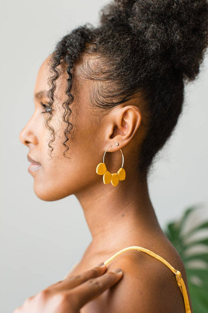Model wearing mustard-yellow leather petal hoop earrings in profile
