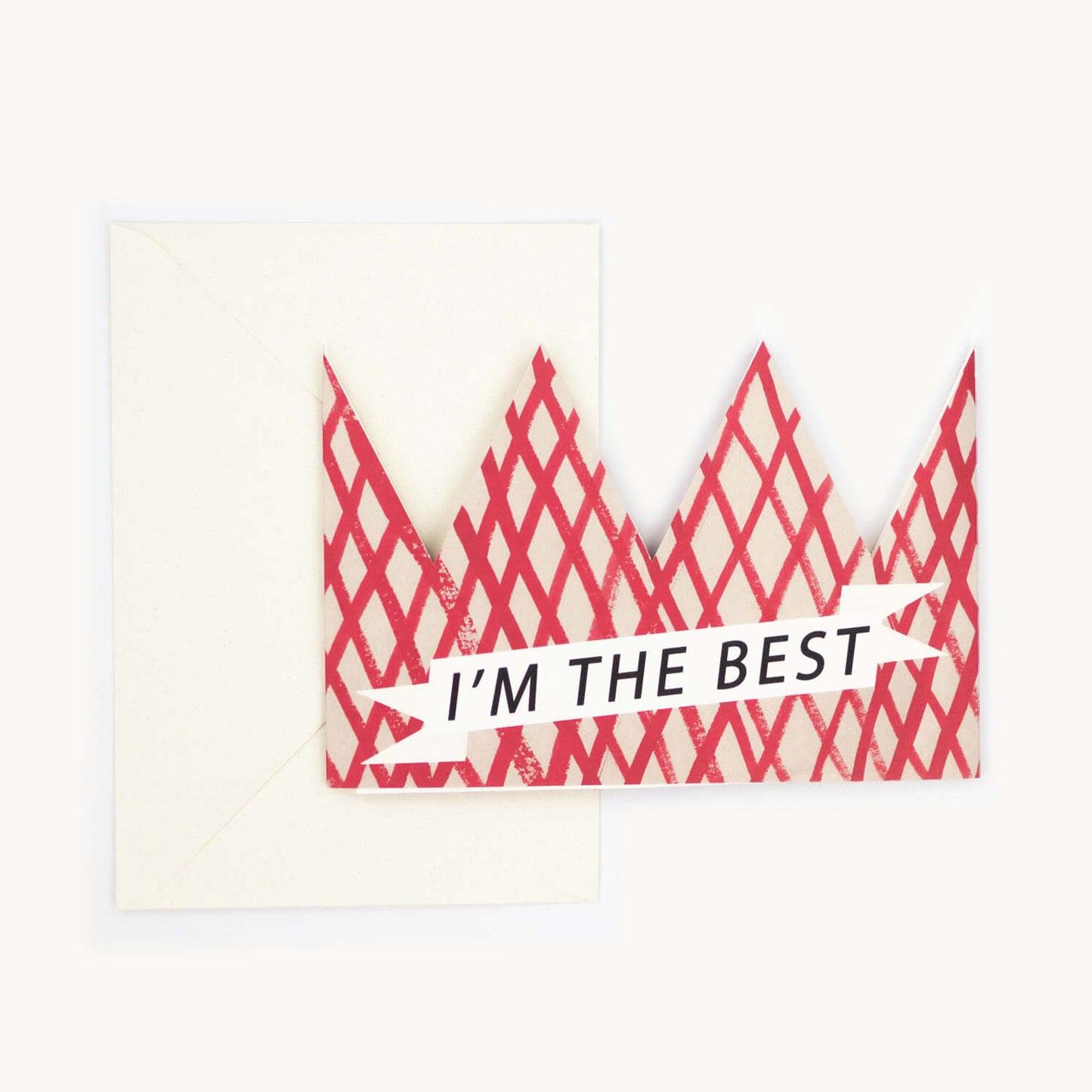 Cream party hat crown card with a red diamond lattice pattern and a white banner reading 'I'M THE BEST,' cream envelope behind