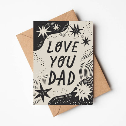 'Love You Dad' Father's Day card featuring hand-lettered text surrounded by illustrated stars and constellations on a cream and black background