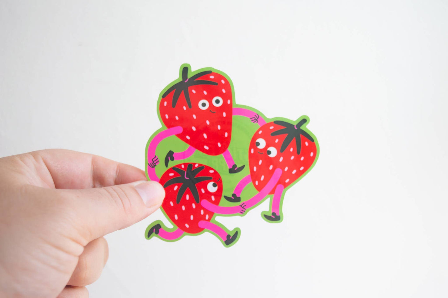 Strawberry Dance Vinyl Sticker — illustration of three strawberry characters with arms and legs holding hands in a circle