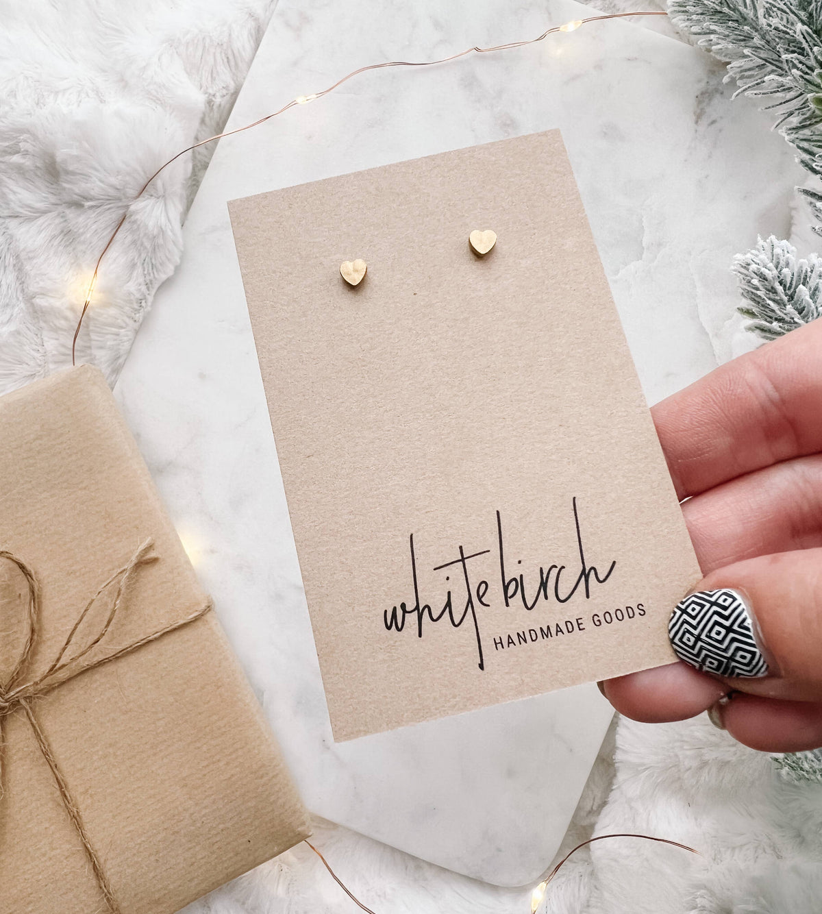 Mini brass heart stud earrings displayed on kraft earring card