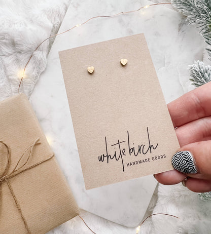 Mini brass heart stud earrings displayed on kraft earring card