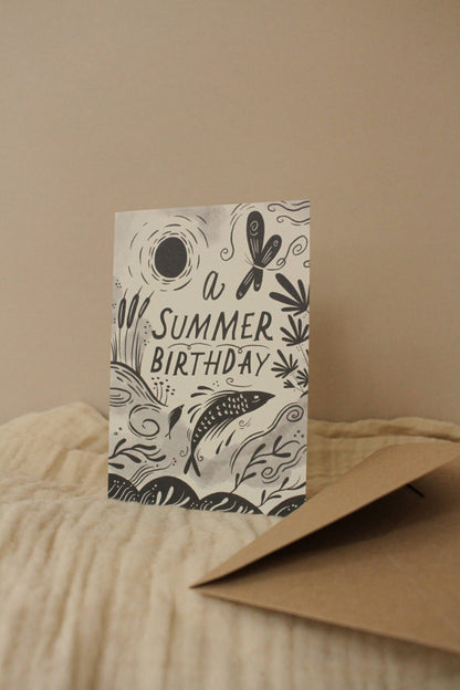 'A Summer Birthday' card with kraft envelope on a light background