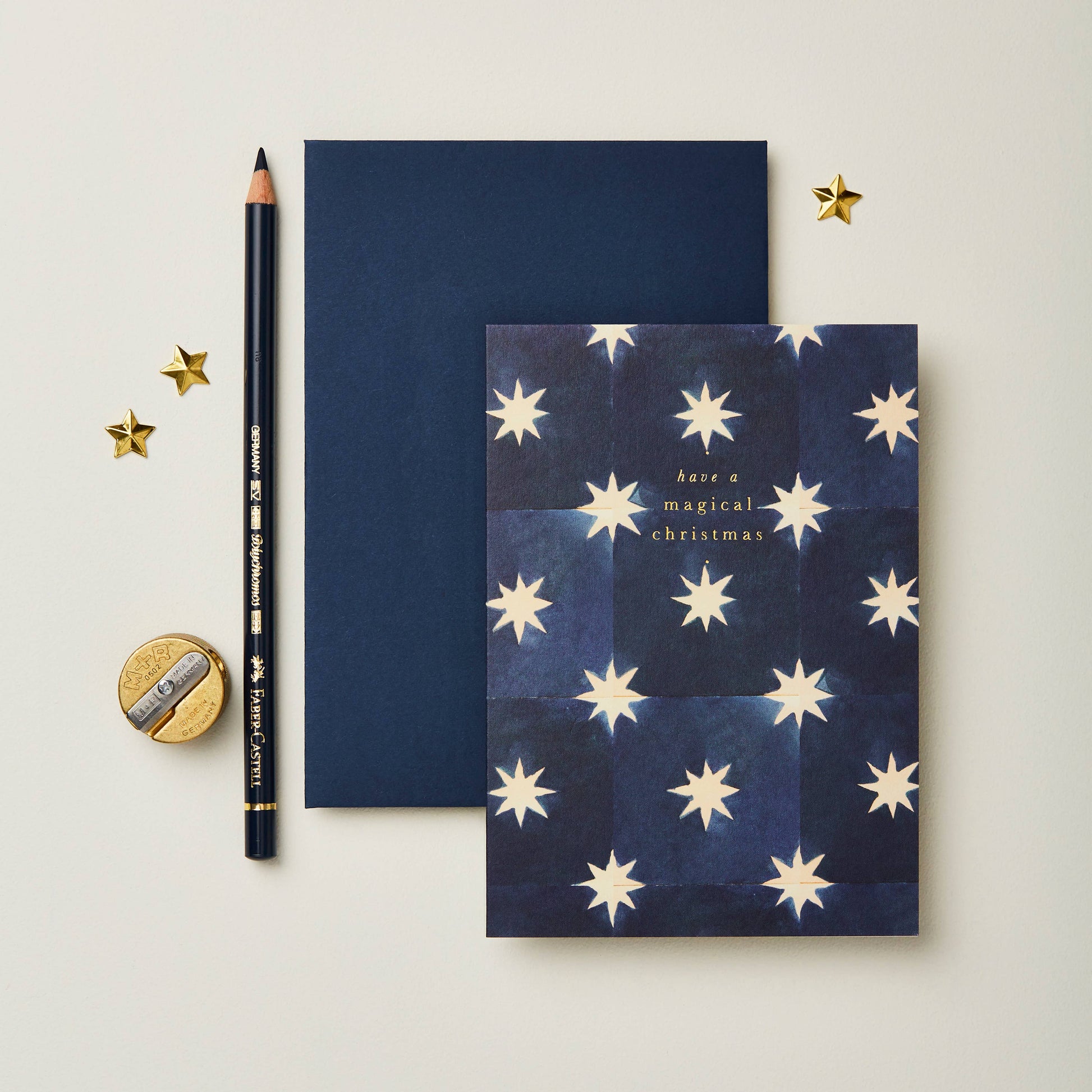 Navy blue Christmas card with a gold star tile pattern, reading Have a Magical Christmas
