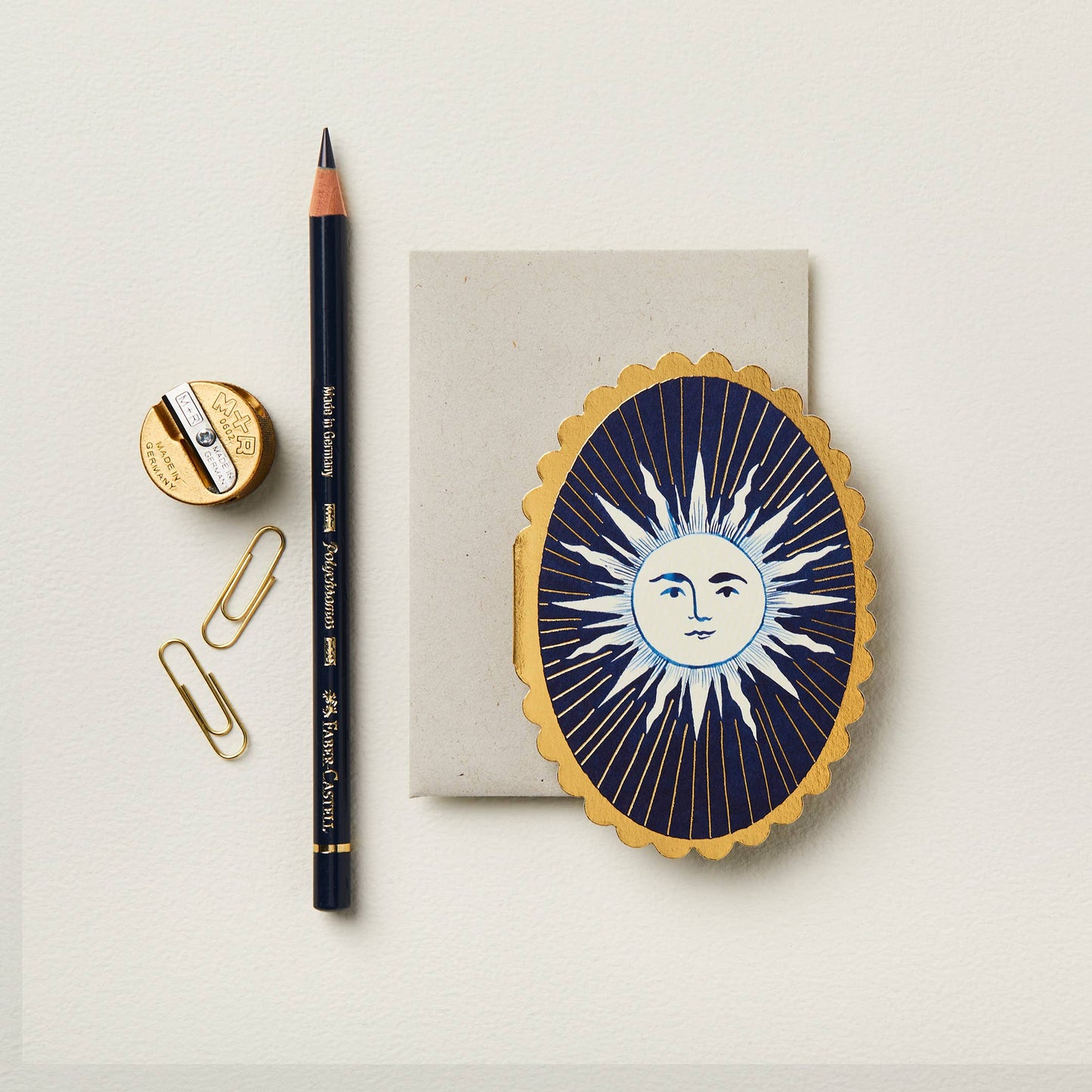 Navy blue oval mini card with a gold and white illustrated sun face design