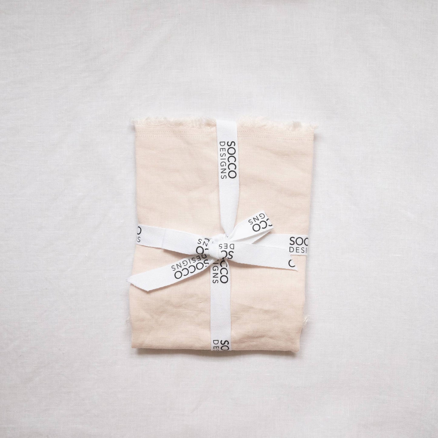 Close-up of the blush fringed linen lumbar pillow cover showing the frayed edge texture