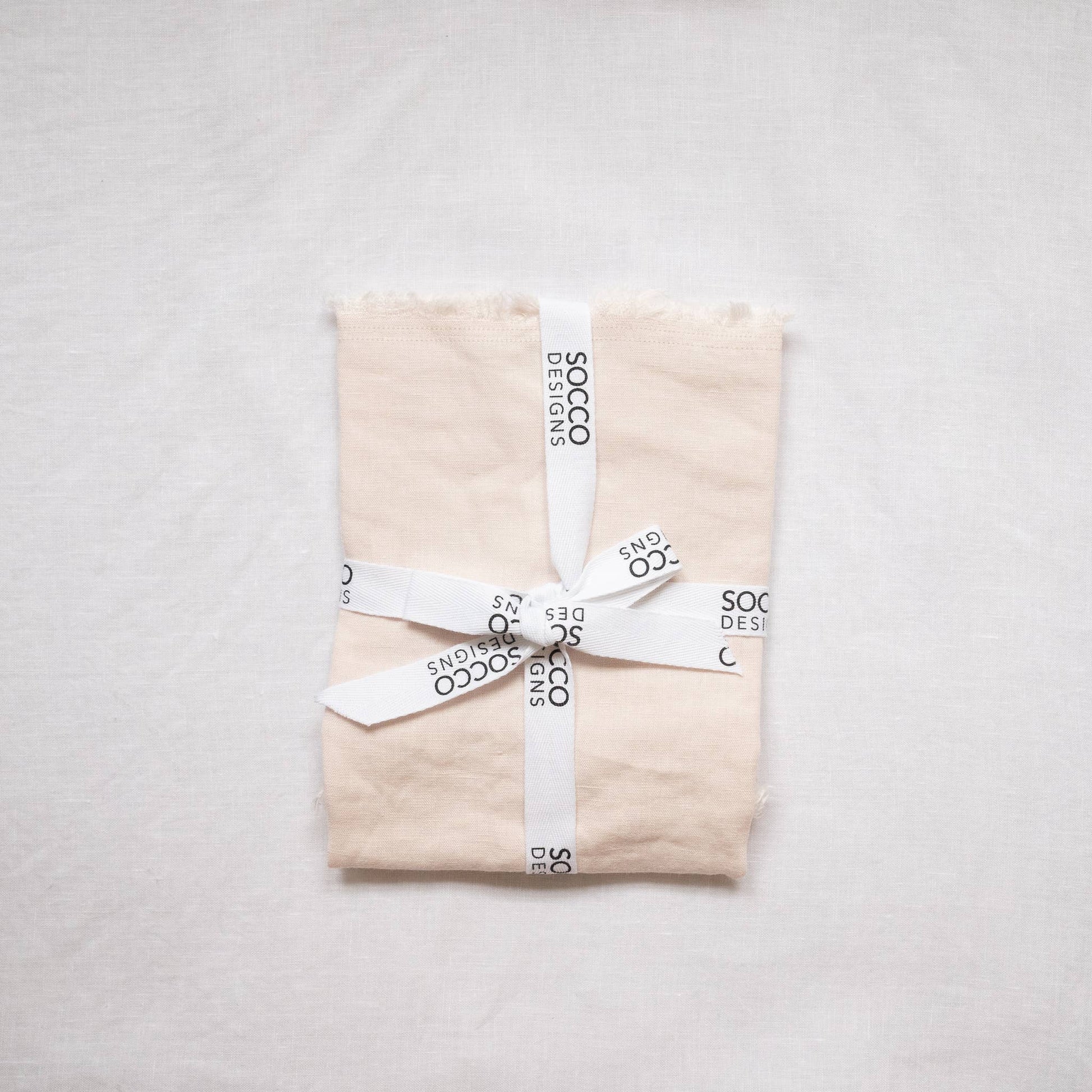 Close-up of the blush fringed linen lumbar pillow cover showing the frayed edge texture