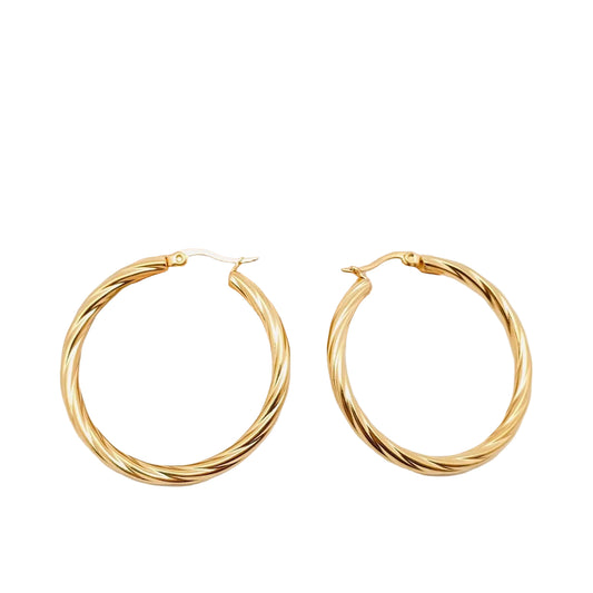 Gold hoop earrings on a light gray background with a wooden block.