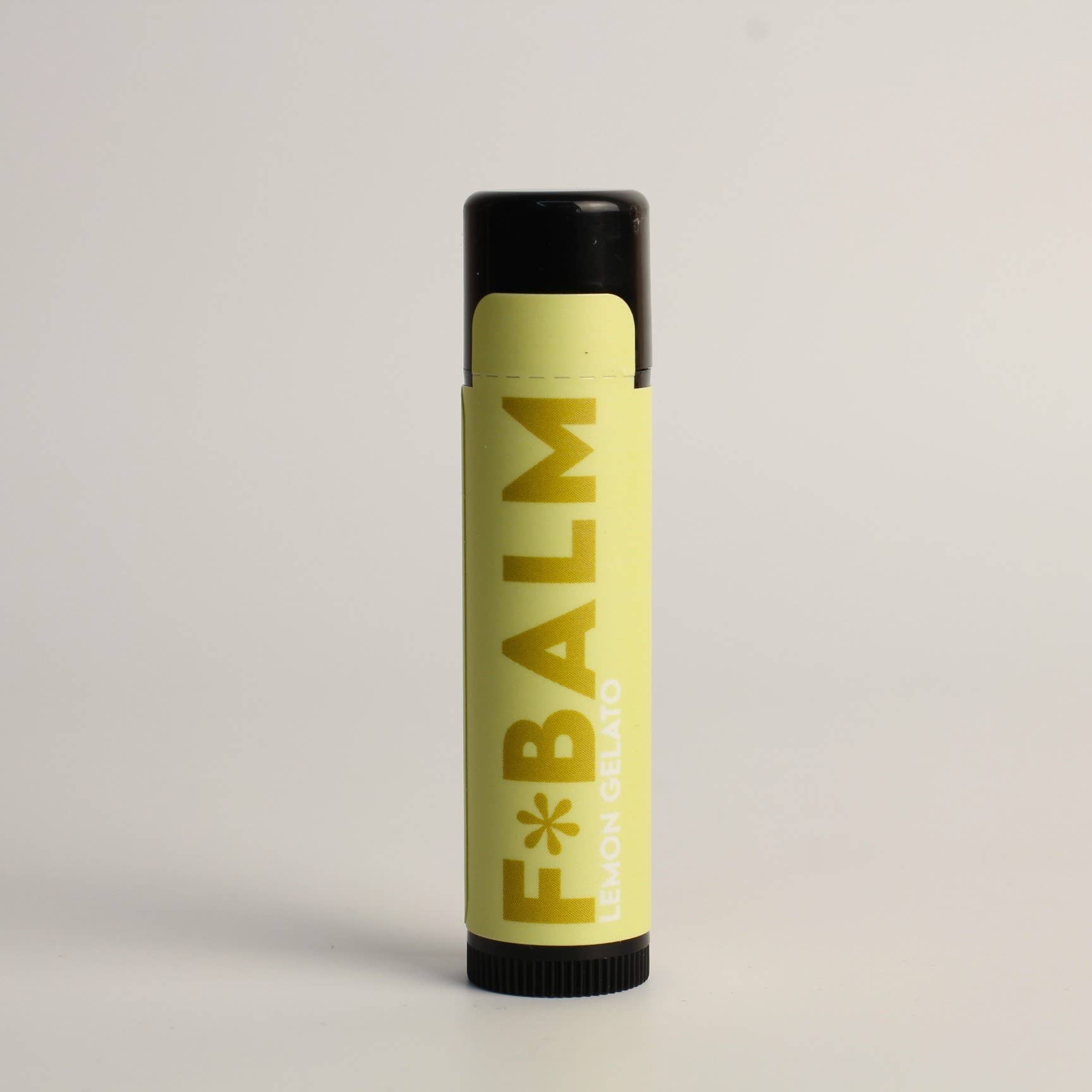 Charleston & Harlow F*Balm Lemon Gelato lip balm tube with pale yellow kraft-paper label