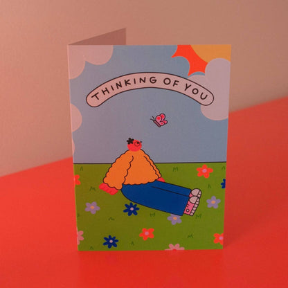 Thinking of You greeting card illustrated with a person lying in grass under a blue sky with a butterfly - PABOOM