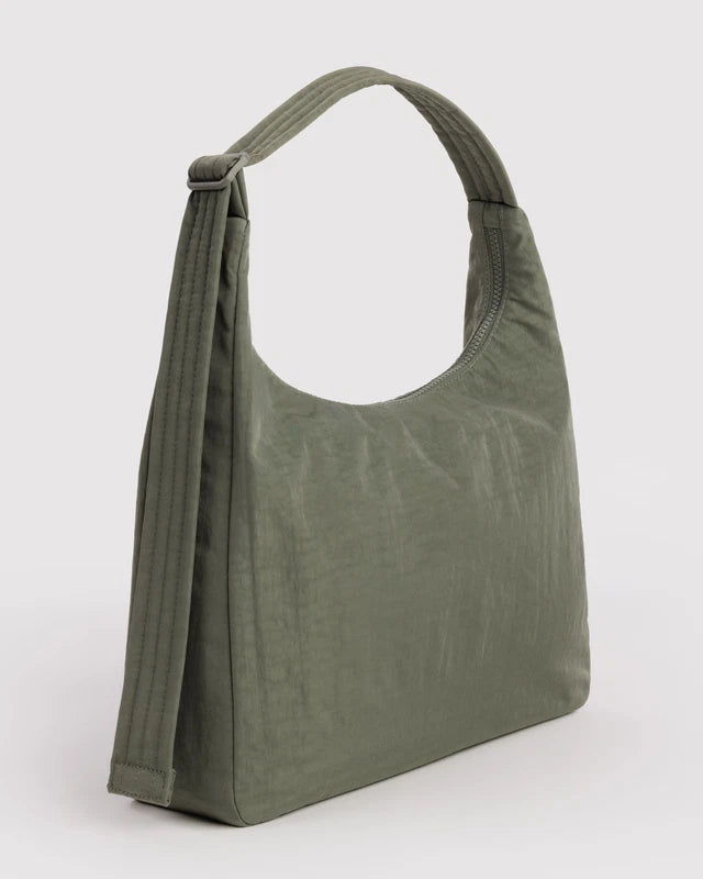 BAGGU Nylon Shoulder Bag in caper green worn on the shoulder for scale