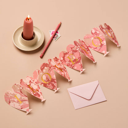 Pink marbled heart-shaped concertina card spelling I LOVE YOU in gold letters