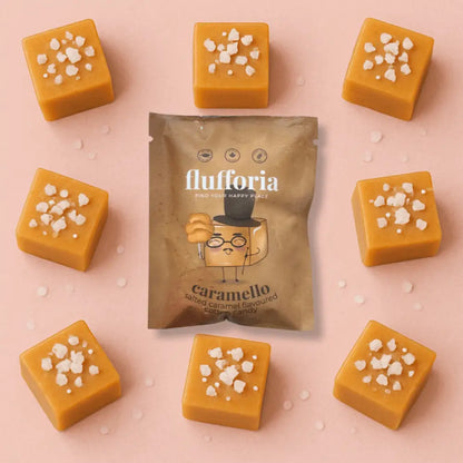 Package of Flufforia’s cotton candy, caramel flavour, brown package. On pink background surrounded by cubes of caramel with salt on top. - PABOOM