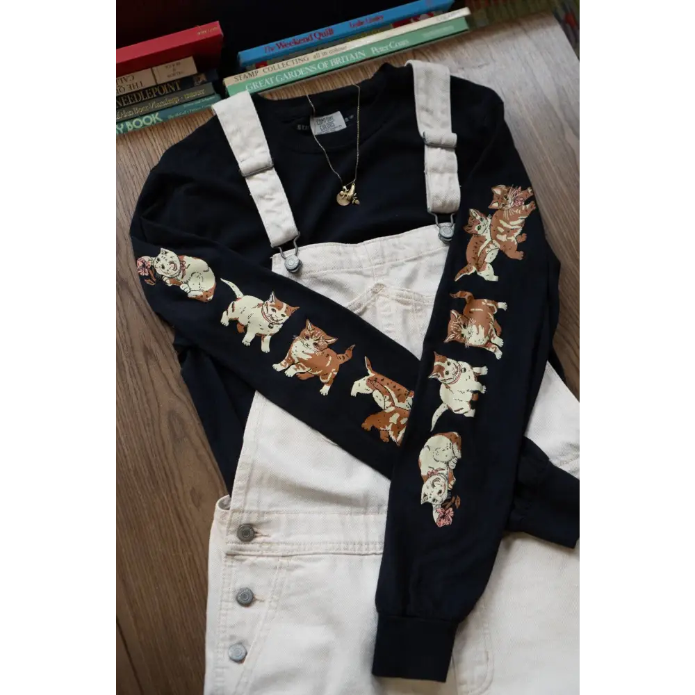 Black Cotton Long Sleeve t-shirt with images of kittens down each sleeve. Cotton, black. White overalls overtop -  PABOOM